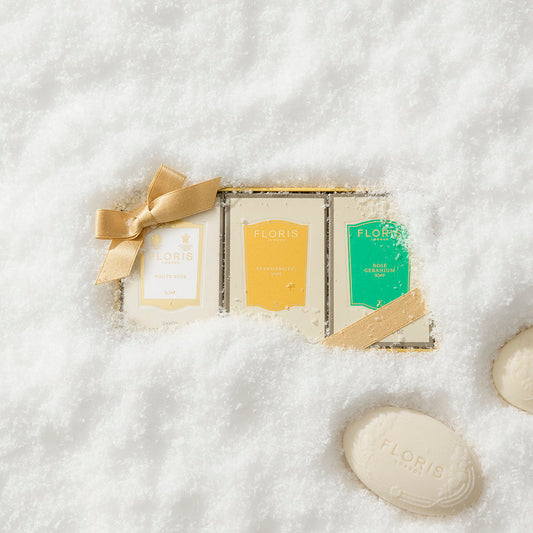 Three Floris London US Soap Collection | For Her bars in a gold box with bows, surrounded by snow and two loose bars—floral elegance and signature scents.
