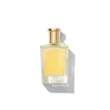 A Floris London Stephanotis Bath Essence bottle, glass with a gold cap, on white background. Features a gold-accented yellow label hinting at stephanotis blossom.