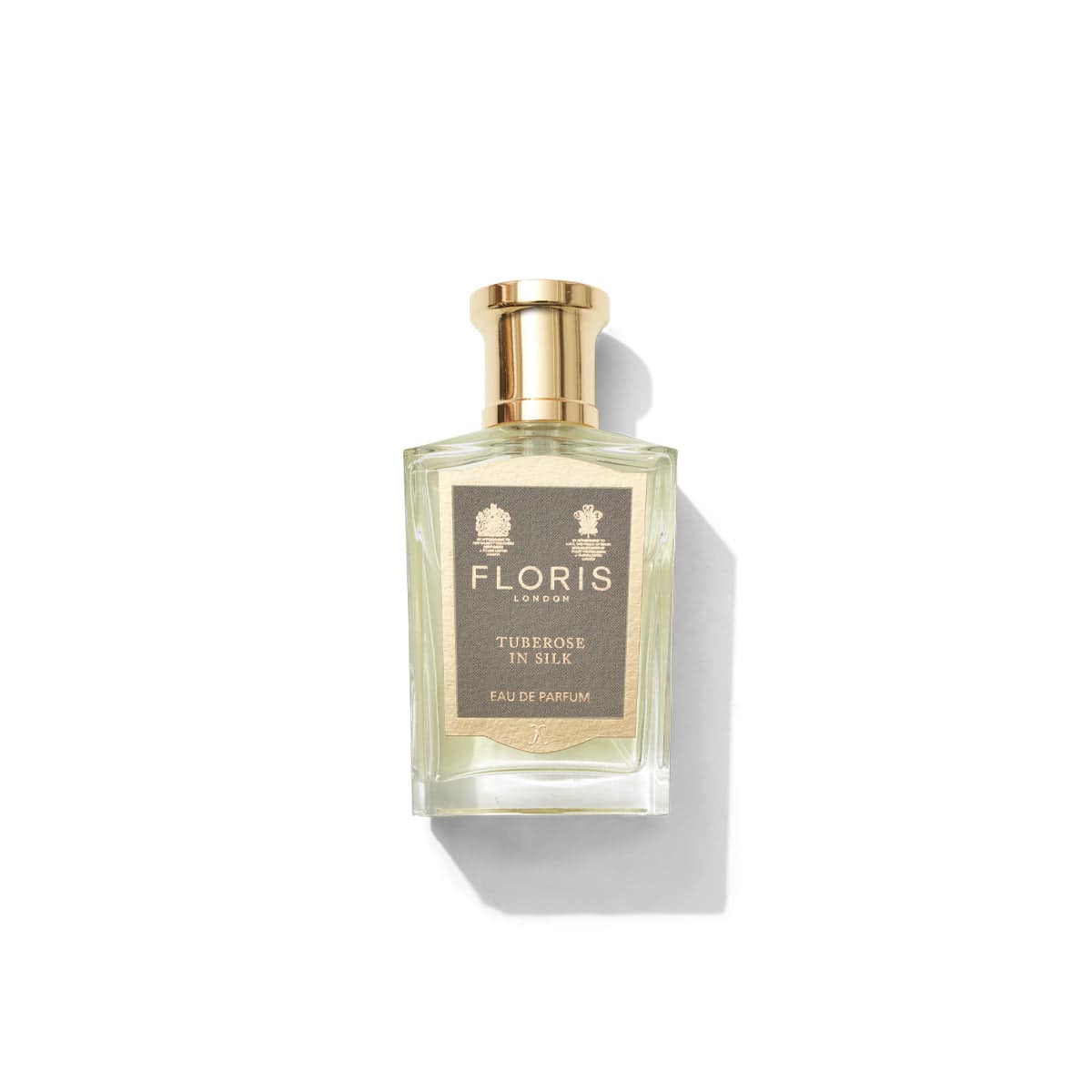 A bottle of Floris London Tuberose In Silk - Eau de Parfum, adorned with a gold cap and label, sits gracefully on a white background, radiating an enchanting scent of tuberose and jasmine.