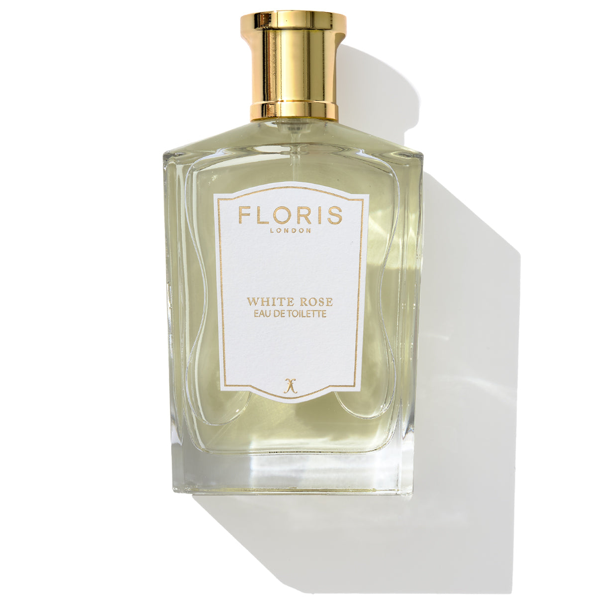 A bottle of White Rose - Eau de Toilette by Floris London, featuring a gold cap and label, set against a white background. The fragrance elegantly intertwines velvet roses with subtle hints of warm amber.