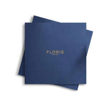 Two stacked blue booklets titled "2024|25 Catalogue" with "Floris London" in gold text on the cover, reminiscent of a refined coffee table book.