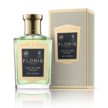 A bottle and box of Floris London's Lily of the Valley Bath Essence, featuring a gold and blue label, offers a delightful floral green scent.